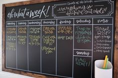 a blackboard with chalk writing on it next to a white cup and pen holder