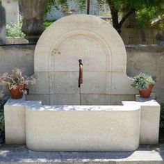 a fountain in the middle of a garden with potted plants