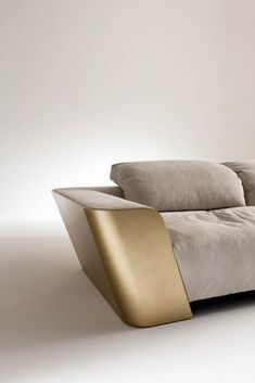 a couch with two pillows on top of it in front of a white wall and floor