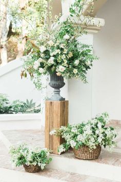 some white flowers are in baskets on the steps