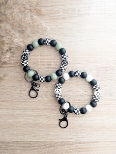 two bracelets with black and white beads are sitting on a wooden table next to each other