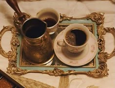 two cups of coffee sit on a tray next to an ornate spoon and fork,