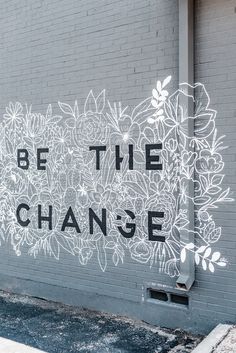 graffiti on the side of a building that says be the change with flowers painted on it