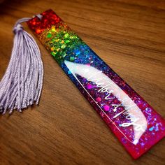 a bookmark with a tassel on it sitting on a wooden table next to a keychain