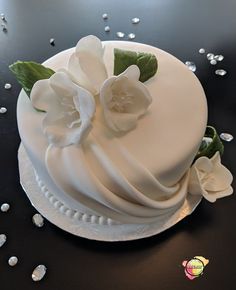 a cake with white frosting and flowers on it sitting on top of a table