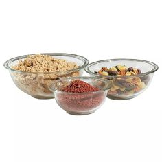 three glass bowls filled with different types of cereals and other food items on a white background