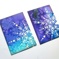 two snowflakes are sitting on top of each other, one is blue and the other is purple