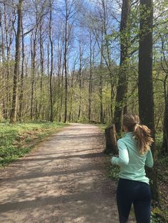 a woman running down a path in the woods