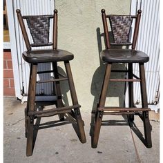 two wooden barstools sitting next to each other in front of a white building