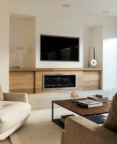 a living room with couches, tables and a television mounted on the wall above it