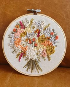 a close up of a embroidery on a brown leather couch with flowers in the center