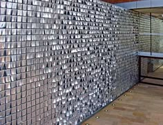 a wall made out of silver tiles in a room with wooden floors and walls behind it