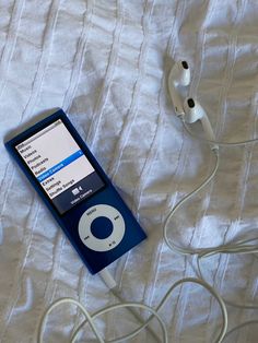 an ipod is plugged in to a charger on a bed with headphones