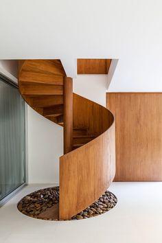 a wooden spiral staircase next to a glass door in a room with white walls and flooring