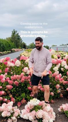 a man is standing in the middle of some flowers