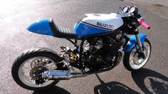 a blue and white suzuki motorcycle parked on the street