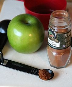 an apple and spices sit on a cutting board