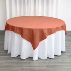 an orange and white table cloth on top of a round table