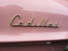 the name cadillac on the front of a pink car