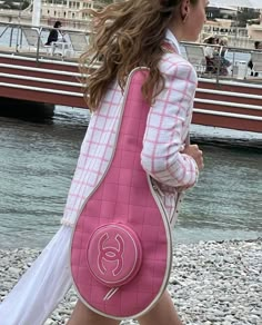 a woman is walking down the beach carrying a pink handbag in front of her