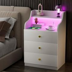 a white night stand with pink lights on it in a bedroom next to a bed