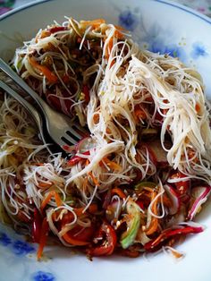 a bowl filled with noodles and veggies on top of a floral table cloth