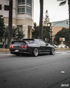 the car is parked on the side of the road in front of some palm trees