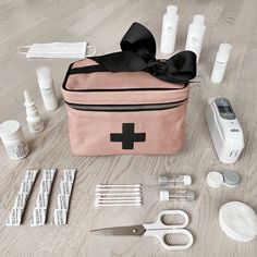 the contents of a personal care bag laid out on a wooden floor with scissors, toothpaste, and other items