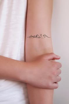 a woman's arm with a small tattoo on the left side of her arm