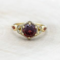 a close up of a ring with a red stone in the middle and white diamonds around it