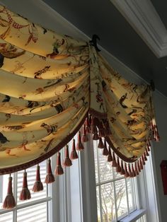 a window curtain with tassels hanging from it's sides in front of a window