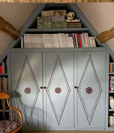 a book shelf with many books on top of it and a chair in front of it