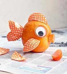 a paper mache fish sitting on top of a piece of paper with orange and white polka dots