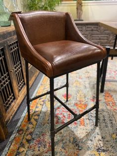 a brown leather bar stool sitting on top of a rug