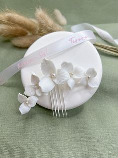 Exquisite and elegant, this White Porcelain Flower Bridal Hair Comb is the perfect accessory to grace any bride's hairstyle on her special day. Handcrafted with delicate white clay, each flower on this comb is accentuated with a lustrous pearl at its center, offering a sophisticated touch of glamour. Designed for versatility and beauty, this bridal hair comb fits seamlessly into both classic and contemporary wedding themes. Its sturdy construction ensures it stays securely in place, whether you' Bride's Hairstyle, Flower Bridal Hair, Elegant Wedding Hair, Wedding Hair Jewelry, Bridal Hair Piece, Bridal Hair Flowers, Flower Hair Comb, Special Clothes, Contemporary Wedding