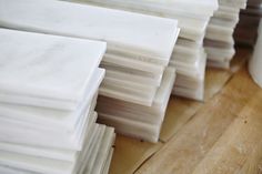 several stacks of white tiles sitting on top of a wooden floor next to each other