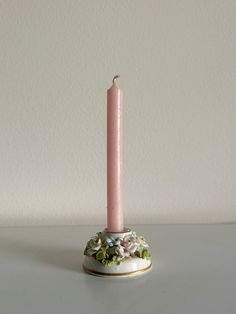 a pink candle is sitting on a white table