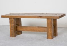 a wooden bench sitting on top of a cement floor next to a white wall in an empty room