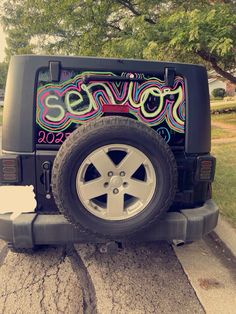 a jeep parked on the side of a road with graffiti painted on it's doors