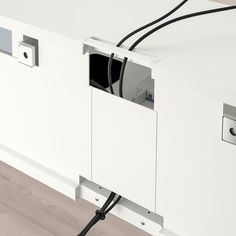 an electronic device is plugged into the side of a white cabinet with wires attached to it