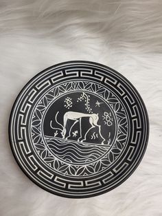 a black and white plate with an animal on it's side, sitting on a fur surface