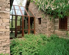 an old stone house with large windows in the grass