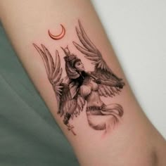 a woman's arm with an angel tattoo on it and a crescent moon in the background