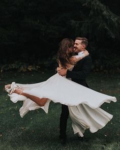 a man and woman are dancing in the grass with their arms wrapped around each other