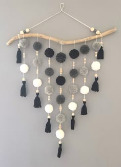 a wall hanging with black and white balls, tassels and pom - poms