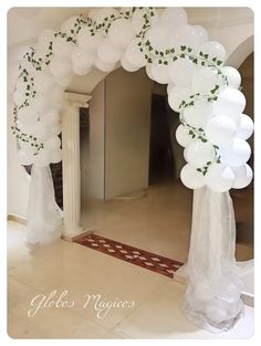 an arch made out of white balloons and greenery