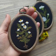 two embroidered flowers are being held by someone's hand