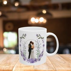 a white coffee mug with a photo of a bride and groom on the front is sitting on a wooden table