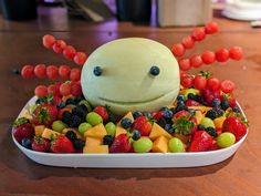 a plate filled with fruit and a smiling face made out of watermelon on top