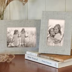 two frames sitting next to each other on top of a wooden table with flowers in the background